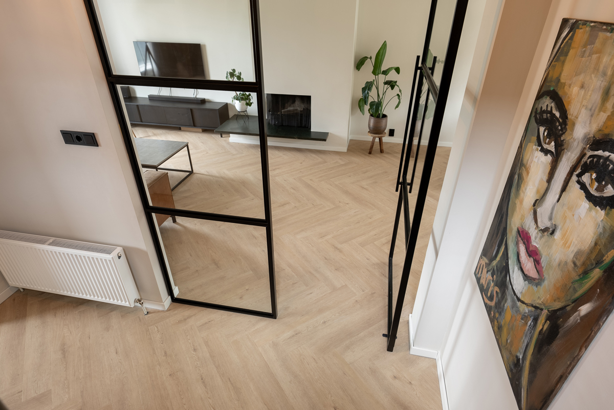 Floer Walvisgraat PVC Gaia Grijsbeige FLR-3527 plak PVC visgraat gelegd in een warm ingericht interieur